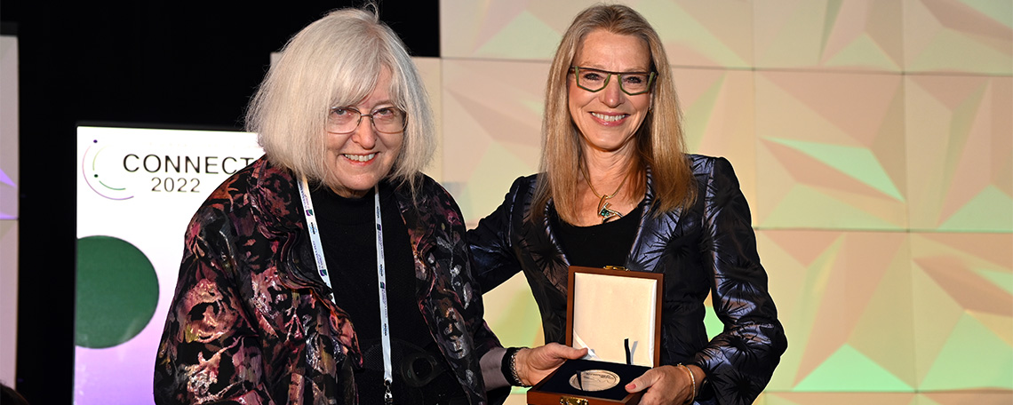 A woman receives an award on a conference stage.